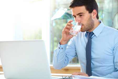 Portrait of a relaxed young businessman sitting in a bright officeの写真素材