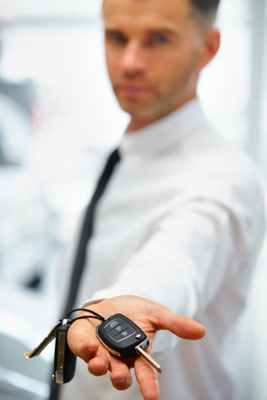 Car Salesman Giving Key of New Car at Showroomの写真素材