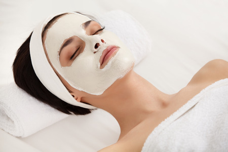 Cosmetic Mask. Beautiful Young Woman Getting a Beauty Treatment in Spa Salon. Isolated on White Backroundの写真素材