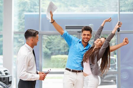 Young Couple Celebrating Purchase of a car In Car Showroomの写真素材