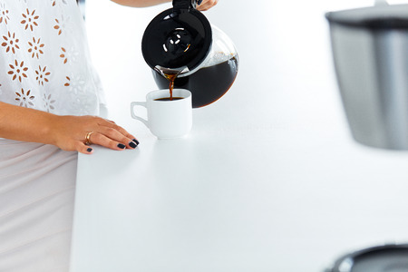 Woman\'s hand with beautiful manicure pouring herself a mug of hot filtered coffee from a glass pot on her break.の写真素材