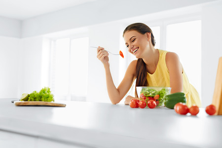 Healthy Diet. Beautiful Smiling Woman Eating Fresh Organic Vegetarian Salad In Modern Kitchen. Healthy Eating, Food And Lifestyle Concept. Health, Beauty, Dieting Concept.