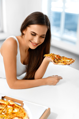 Eating Fast Food. Close-up Of Happy Beautiful Healthy Woman Eating Italian Pizza At Home. Nutrition And Dieting. Diet And Lifestyle Concept.の写真素材