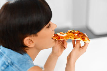 Eating Fast Food. Close-up Of Happy Beautiful Healthy Woman Eating Italian Pizza At Home. Nutrition And Dieting. Lifestyle Concept.の写真素材