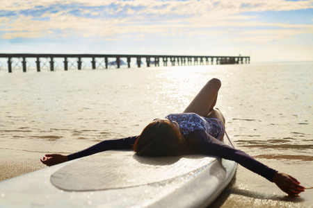 Summer Relaxation. Healthy Happy Woman With Fit Body Relaxing On Beach, Lying On SUP, Surf Board Near Sea ( Ocean, Water ). Holidays Travel Vacation. Lifestyle, Freedom, Wellness, Happiness Concept.の写真素材