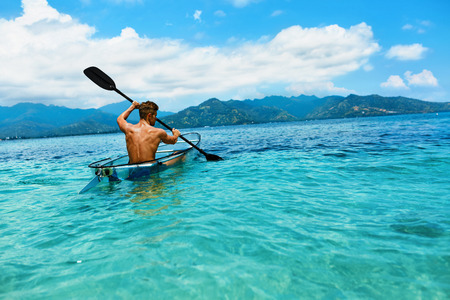 Summer Travel Kayaking. Man Paddling Transparent Canoe Kayak In Tropical Ocean, Enjoying Recreational Sporting Activity. Male Canoeing With Paddle, Exploring Sea On Vacation. Rowing Water Sportsの写真素材