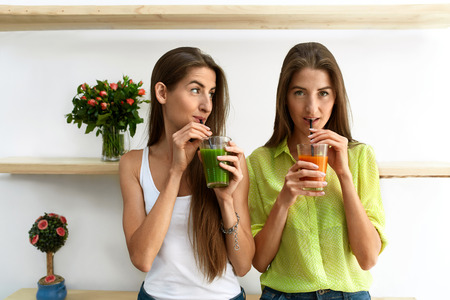 Detox Juice For Healthy Nutrition. Beautiful Happy Smiling Women Drinking Fresh Vegetable Detox Juice Smoothie Home. Twin Girls Enjoying Vegan Weight Loss Drink In Dining Room. Fitness Diet Conceptの写真素材