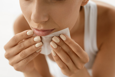 Skin Care. Woman Removing Oil From Face Using Blotting Papers. Closeup Portrait Of Beautiful Healthy Girl With Nude Makeup Cleaning Perfect Soft Skin With Oil Absorbing Tissue Sheets. Beauty Conceptの写真素材