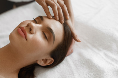 Spa Massage. Closeup Of Beautiful Healthy Woman Getting Face Massage At Salon. Female Enjoying Facial Beauty Treatment While Masseur Hand Massaging Her Head. Skin Care Concept. High Resolution Imageの写真素材