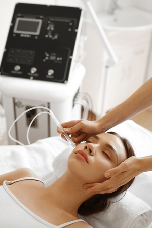Face Beauty Treatment. Closeup Of Beautiful Woman Getting Facial Gas-liquid Oxygen Water Epidermal Peeling Using Professional Equipment At Cosmetology Center. Skin Care Concept. High Resolution Imageの写真素材