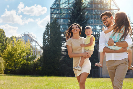 Happy Family Portrait In Nature. Beautiful Smiling Young Parents And Children Spending Time Together In Park. Mother, Daughter, Father And Son  Having Fun Outdoors. Love And Relationships Concept.の写真素材