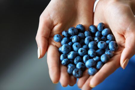 Healthy Organic Food. Closeup Of Young Woman Hands With Natural Nails Holding Fresh Tasty Juicy Ripe Sweet Blueberries ( Blue Berries ). Vegetarian Food Concept. Diet Lifestyle. High Resolution Imageの写真素材