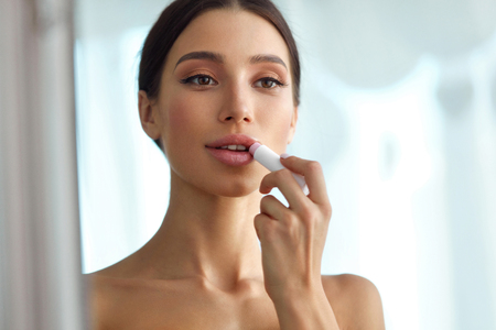 Lips Protection. Beautiful Woman With Beauty Face, Sexy Full Lips Applying Lip Balm, Lipcare Stick On. Portrait Of Female Model With Natural Makeup. Lips Skin Care Cosmetics Concept. High Resolutionの写真素材