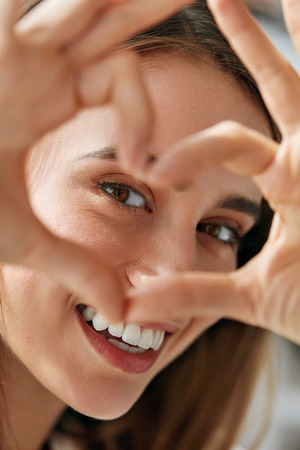 Healthy Eyes And Vision. Portrait Of Beautiful Happy Woman Holding Heart Shaped Hands Near Eyes. Closeup Of Smiling Girl With Healthy Skin Showing Love Sign. Eyecare. High Resolution Imageの写真素材