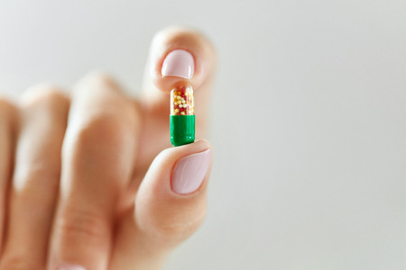 Medicine. Closeup Of Female Hand Holding Colorful Vitamin Pill In Fingers. Close-up Woman Hand Holding Medication, Medical Capsule. Health Care, Cure Concept. High Resolution Imageの写真素材