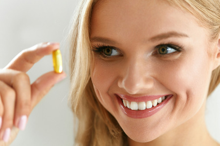 Vitamin And Supplement. Beautiful Smiling Woman Holding Fish Oil Capsule In Hand. Portrait Of Happy Girl Taking Pill With Cod Liver Oil, Omega-3. Diet Nutrition And Healthy Eating Lifestyle Concept.の写真素材