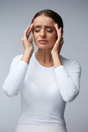 Headache And Stress. Beautiful Young Woman Feeling Strong Head Pain. Portrait Of Tired Stressed Female Suffering From Painful Migraine, Holding Hands Near Face. Health Care Concept. High Resolutionの写真素材