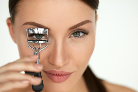 Eyelash Curler. Portrait Of Beautiful Young Woman Using Beauty Tool On Curly Long Eyelashes. Closeup Of Female Model Face With Smooth Skin, Perfect Natural Makeup. High Resolutionの写真素材