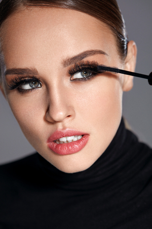 Beauty Make-up. Portrait Of Beautiful Young Woman With Fake Eyelashes Applying Black Mascara On Lashes, Holding Brush In Hand. Sexy Female With Soft Skin And Perfect Makeup. Cosmetics. High Resolutionの写真素材