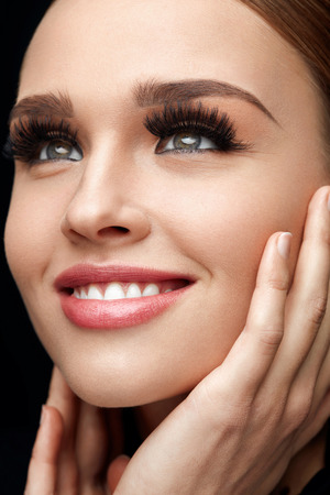 Beauty Woman Face. Closeup Of Glamorous Girl With Hands Touching Soft Smooth Skin. Portrait Of Beautiful Sexy Woman With Perfect Facial Makeup And Long Black Fake Eyelashes. Cosmetics. High Resolutionの写真素材