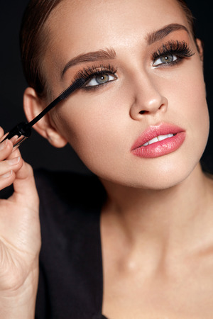 Beauty Make-up. Portrait Of Beautiful Young Woman With Fake Eyelashes Applying Black Mascara On Lashes, Holding Brush In Hand. Sexy Female With Soft Skin And Perfect Makeup. Cosmetics. High Resolutionの写真素材