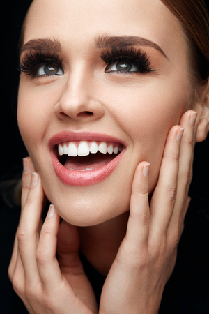 Beauty Woman Face. Closeup Of Glamorous Girl With Hands Touching Soft Smooth Skin. Portrait Of Beautiful Sexy Woman With Perfect Facial Makeup And Long Black Fake Eyelashes. Cosmetics. High Resolutionの写真素材