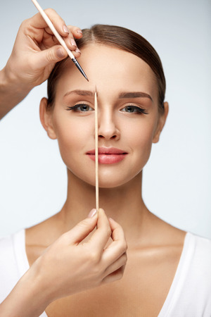 Woman Beauty. Portrait Of Beautiful Smiling Female Model With Perfect Skin, Face Makeup. Closeup Of Sexy Girl Modelling Eyebrows Shape With Stick And Brow Brush. Brows Correction. High Resolutionの写真素材