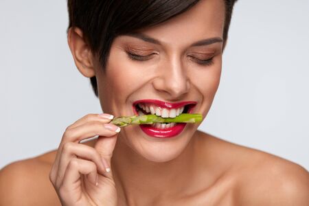 Healthy Foods. Woman Eating Fresh Asparagus. Portrait Of Smiling Vegetarian Girl With Beautiful Face Makeup Holding Organic Green Vegetable In Mouth. Diet Nutrition, Health Concept. High Resolutionの写真素材