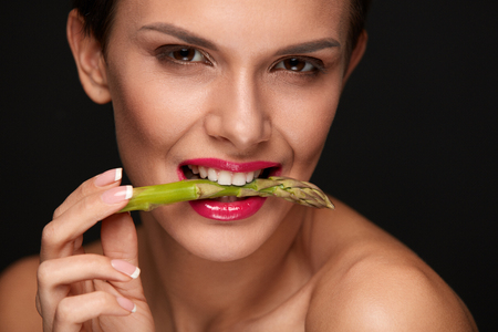 Healthy Foods. Woman Eating Fresh Asparagus. Portrait Of Smiling Vegetarian Girl With Beautiful Face Makeup Holding Organic Green Vegetable In Mouth. Diet Nutrition, Health Concept. High Resolutionの写真素材