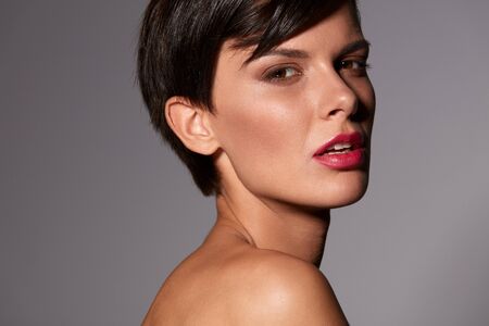 Beauty Woman Face. Portrait Of Beautiful Model Girl With Bright Glamorous Facial Makeup, Healthy Soft Skin, Sexy Pink Lips Posing On Grey Background. Cosmetics And Skin Care Concept. High Resolutionの写真素材