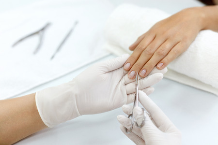 Manicure. Closeup Of Manicurist Hands Removing Cuticle From Female Nails With Professional Metal Nail Scissors. Woman Hand With Healthy Natural Nails Getting Nails Care Procedure. High Resolutionの写真素材