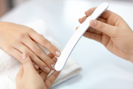 Woman Hands With Nail File. Closeup Of Manicurist Hand Filing Healthy Female Nails With Professional Nail Care Tool In Beauty Salon. Woman Hands With Natural Manicure Polishing Nails. High Resolutionの写真素材