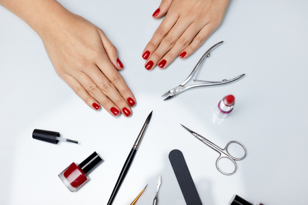 Woman Hands Care. Top View Of Beautiful Smooth Woman's Hands With Professional Nail Care Tools For Manicure On White Background. Closeup Of Healthy Female Nails With Red Nail Polish. High Resolutionの写真素材