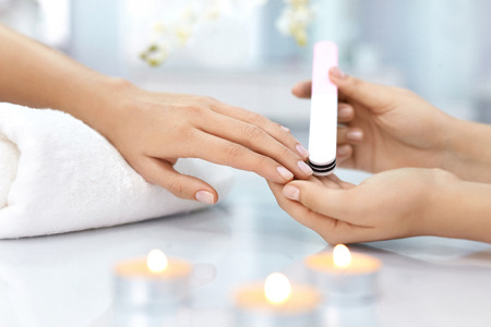Nail Care. Closeup Of Female Hands Filing Nails With Professional Nail File In Beauty Nail Salon. Close-up Of Beautician Hands Doing Perfect Manicure On Woman's Hands. Nail Hygiene. High Resolutionの写真素材