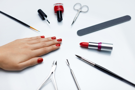 Professional Manicure. Closeup Of Beautiful Woman's Nails With Red Nail Polish With Nail Care Tools On White Table. Close-up Of Female Hand With Perfect Healthy Nails. Beauty Care. High Resolutionの写真素材