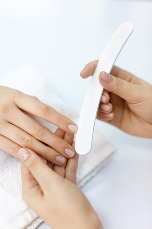 Woman Hands With Nail File. Closeup Of Manicurist Hand Filing Healthy Female Nails With Professional Nail Care Tool In Beauty Salon. Woman Hands With Natural Manicure Polishing Nails. High Resolutionの写真素材