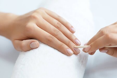 Beauty Care. Closeup Beautiful Woman Hand With Healthy Natural Nails Receiving Cuticle Removing Procedure With Wooden Cuticle Pusher Remover Stick In Salon. Manicure On Female Hands. High Resolutionの写真素材