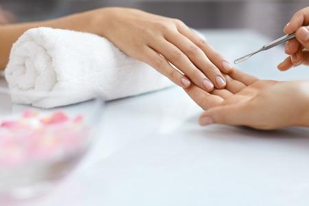 Nail Care At Beauty Salon. Woman Receiving Professional Manicure From Nail Specialist. Closeup Of Female Getting Cuticle Removing Procedure With Metal Pusher Tool. Healthy Fingernails. High Resolutionの写真素材