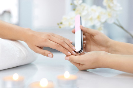Nail Care. Closeup Of Female Hands Filing Nails With Professional Nail File In Beauty Nail Salon. Close-up Of Beautician Hands Doing Perfect Manicure On Woman's Hands. Nail Hygiene. High Resolutionの写真素材