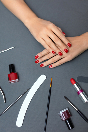 Hands Beauty And Nail Care. Top View Of Beautiful Female Hands With Healthy Nails And Red Nail Polish On Grey Background With Manicure Tools. Closeup Of Female Hands With Nail Tools. High Resolutionの写真素材