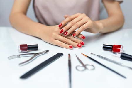 Nail Care. Closeup Of Beautiful Woman Hands Showing Perfect Nails Painted With Red Nail Polish On White Background. Female Hands Near Set Of Professional Manicure Tools. Beauty Care. High Resolutionの写真素材