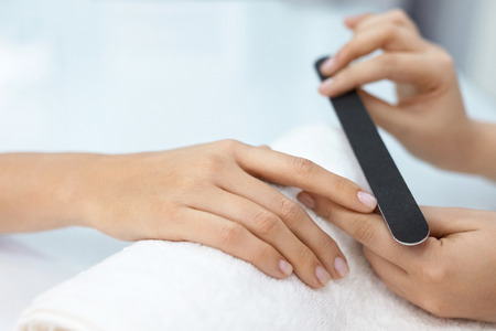Manicure. Close-up Of Female Hands Filing Nails With Nail File In Beauty Salon. Closeup Of Beautiful Woman Hand With Natural Healthy Nails Polishing Nails With Buffer, Nail Care Tool. High Resolutionの写真素材