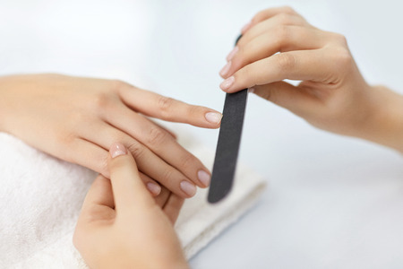 Manicure. Close-up Of Female Hands Filing Nails With Nail File In Beauty Salon. Closeup Of Beautiful Woman Hand With Natural Healthy Nails Polishing Nails With Buffer, Nail Care Tool. High Resolutionの写真素材