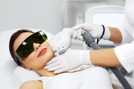 Cosmetology. Beautiful Woman Receiving Laser Hair Removal Procedure At Beauty Salon. Closeup Of Beautician Hands Doing Beauty Treatment For Female Face At Spa Salon. Facial Treatment. High Resolutionの写真素材