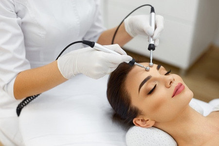 Facial Skin. Closeup Of Beautiful Woman Receiving Facial Microcurrent Treatment From Therapist At Spa Salon. Beautician Using Electrical Impulses For Facial Procedures. Cosmetology. High Resolutionの写真素材