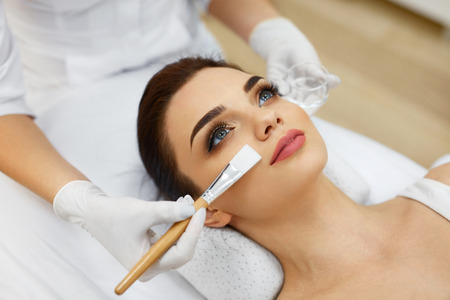 Face Skin Care. Beautician Applying Beauty Oil Mask On Face Using Brush In Spa Salon. Closeup Of Female Client Getting Hydrating Procedure In Beauty Clinic. Cosmetology. High Resolutionの写真素材
