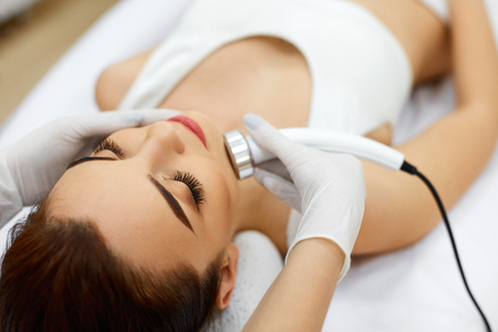 Cosmetology. Beautiful Woman Receiving Facial Skin Ultrasound Cavitation. Closeup Of Female Face Receiving Anti-Aging Cosmetics Using Ultrasound Cavitation Machine. Body Care. High Resolutionの写真素材