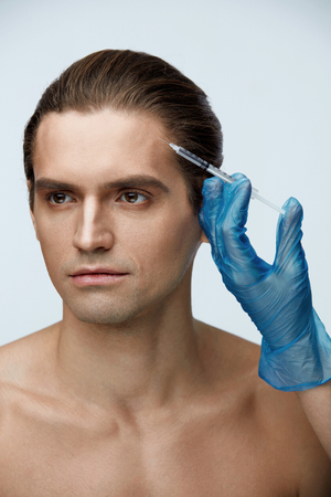 Beauty Care. Portrait Of Handsome Young Male Receiving Facial Injections. Closeup Of Beautician Hand Doing Hyaluronic Acid Injection On Attractive Man's Face. Plastic Surgery Concept. High Resolutionの写真素材