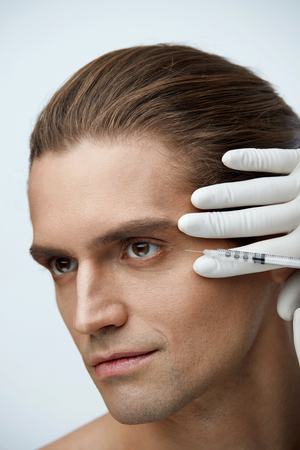 Face Lifting. Closeup Of Doctor's Hands Injecting Hyaluronic Acid Into Man's Facial Skin. Portrait Of Handsome Male Receiving Skin Lift Injection, Beauty Injections. High Resolutionの写真素材