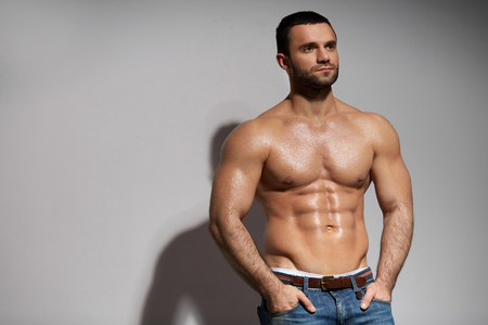 Male Fitness Model With Sexy Muscular Body Portrait. Handsome Hot Young Man With Fit Athletic Body Shape, Perfect Abs Muscles And Naked Torso On Grey Background. Bodybuilding Concept. High Resolutionの写真素材